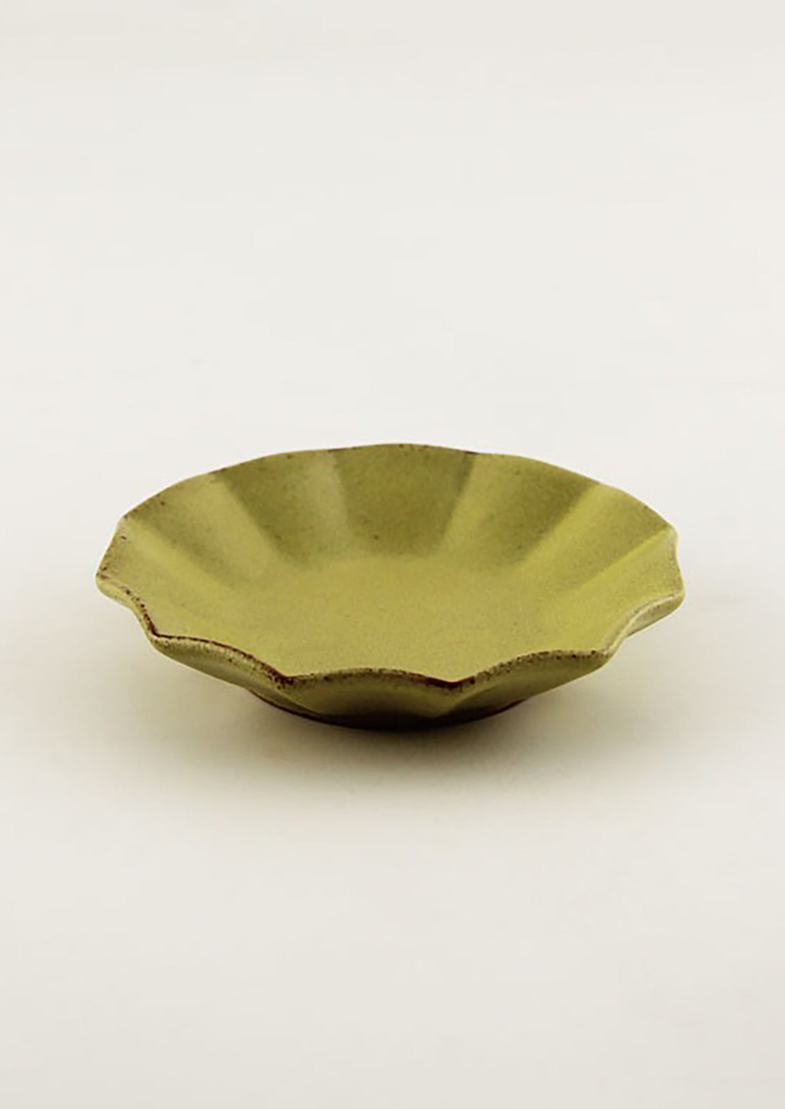 A small round ceramic dish with pleated shape in chartreuse.