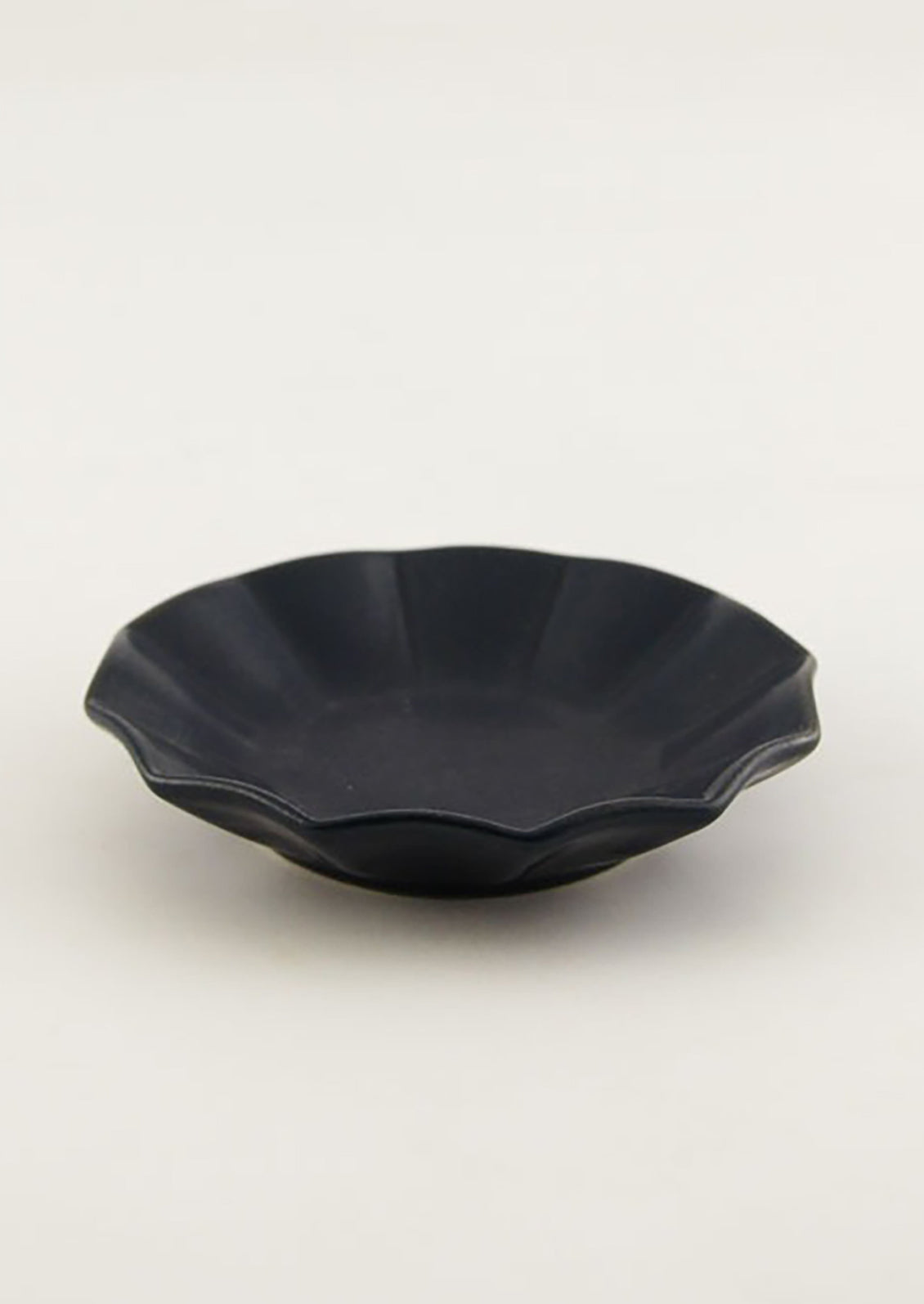 A small round ceramic dish with pleated shape in navy.