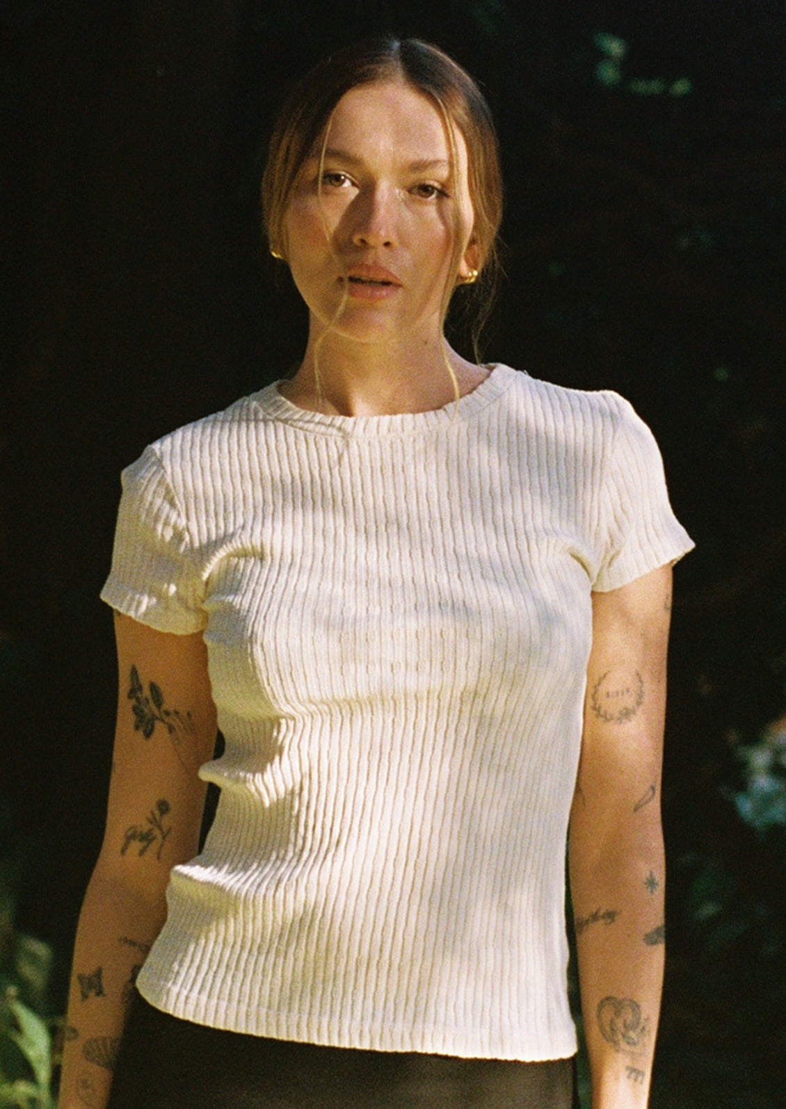 A woman wearing a cream colored pointelle short sleeve tee.