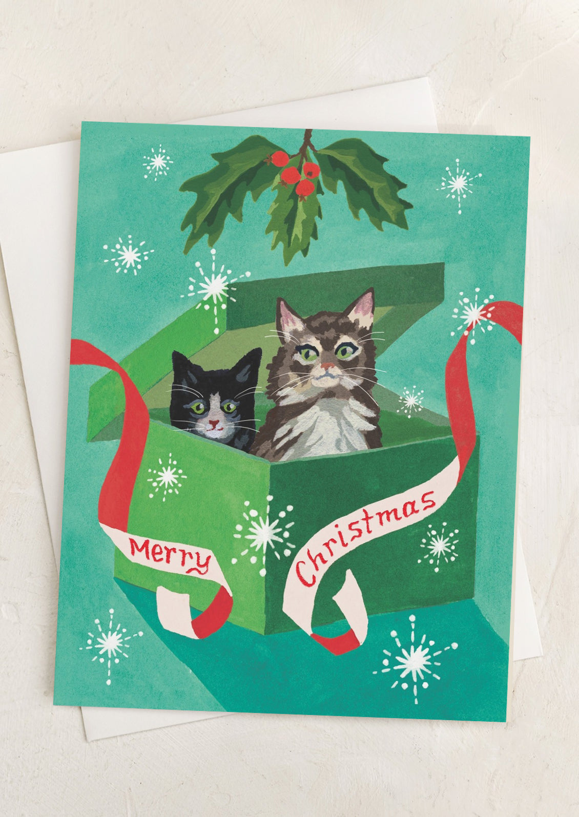 A card with illustration of cats inside a present, text reads Merry Christmas.