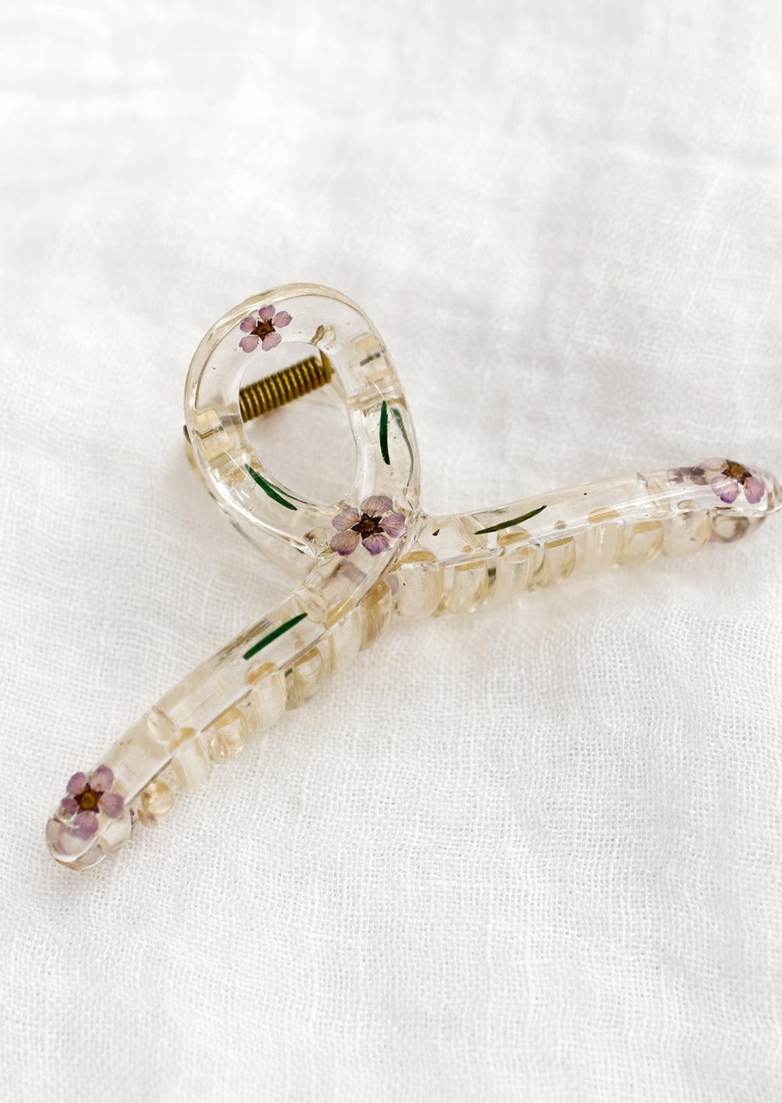 A clear crescent shaped hair claw with purple dried flowers.