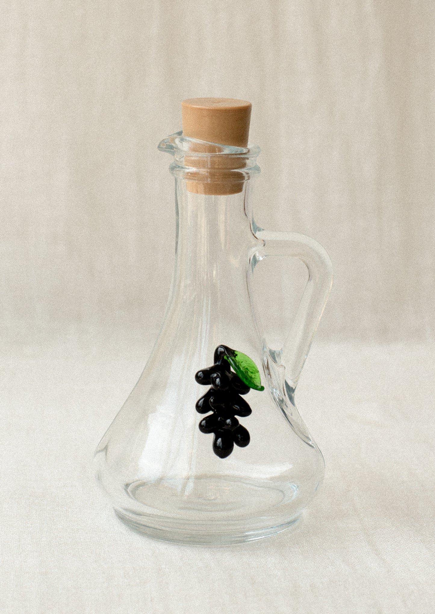 A clear glass cruet bottle with lampwork grape detail.