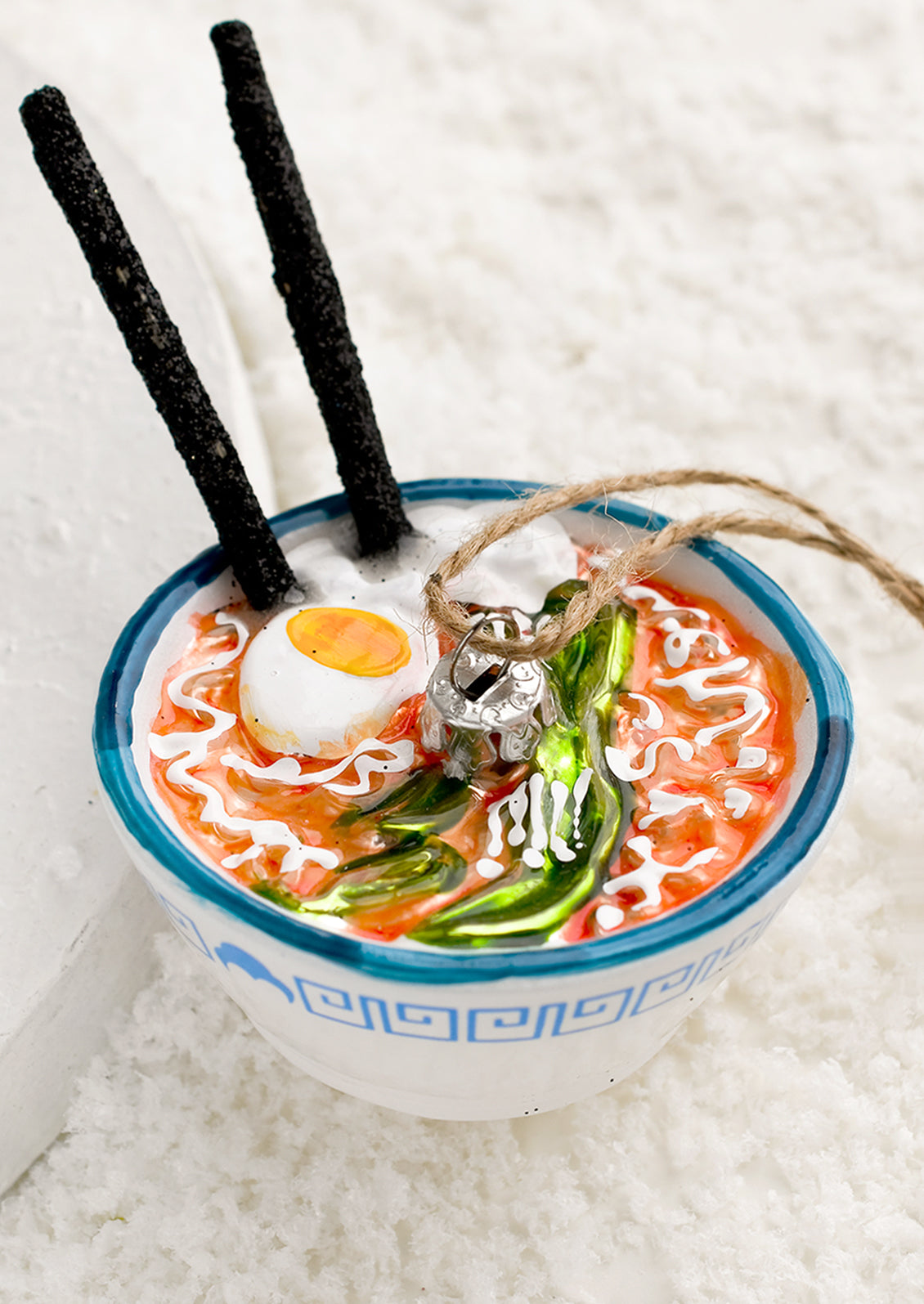 A glass holiday ornament of a bowl of ramen with chopsticks.