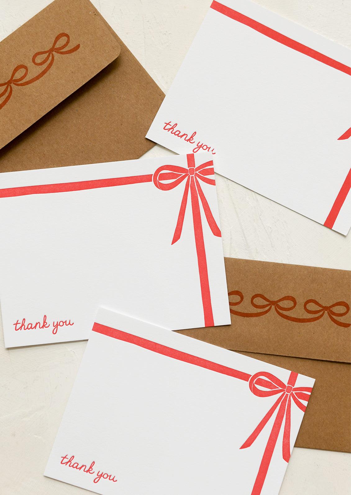 A set of white notecards with red bow detail and text at corner reading "Thank you".