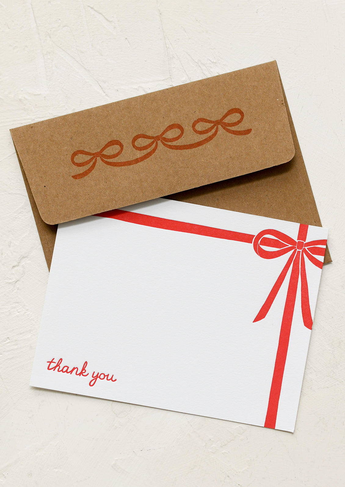 A white notecard with red bow detail and text at corner reading "Thank you".