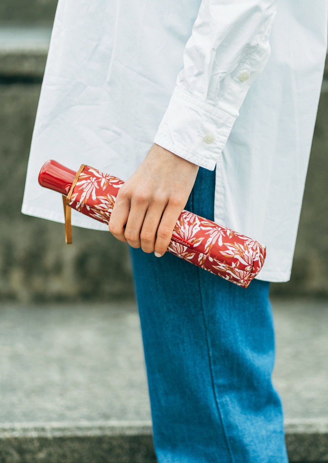 A woman holding a red floral print umbrella.