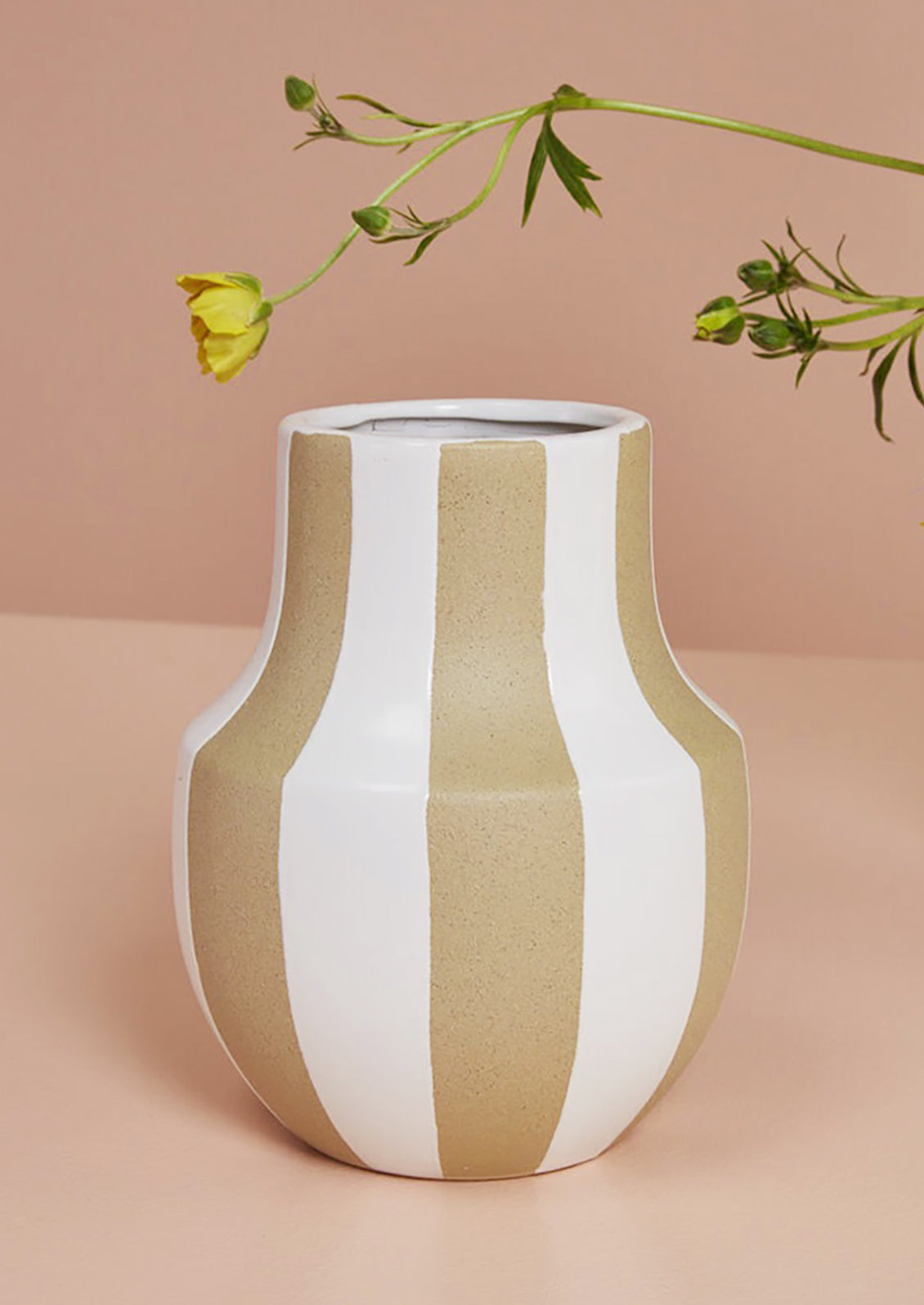 A sand ceramic vase with vertical white stripes and sculptural shape.