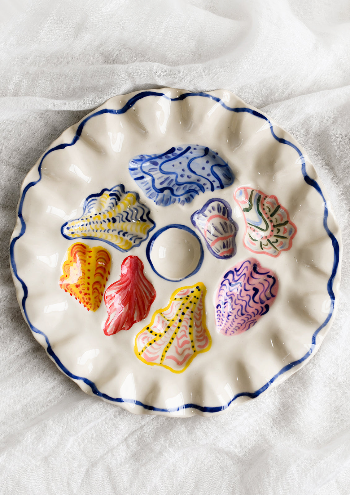 A handmade ceramic oyster plate with colorful painted oyster design.