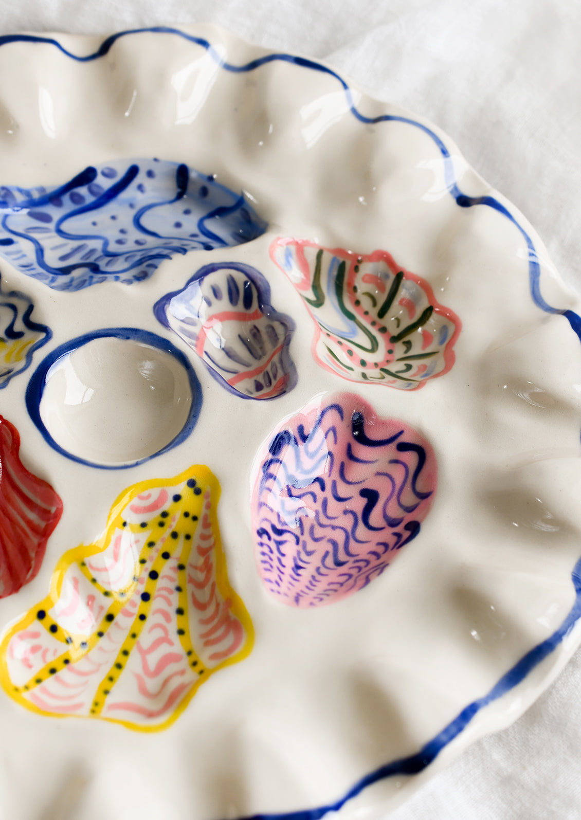 A handmade ceramic oyster plate with colorful painted oyster design.