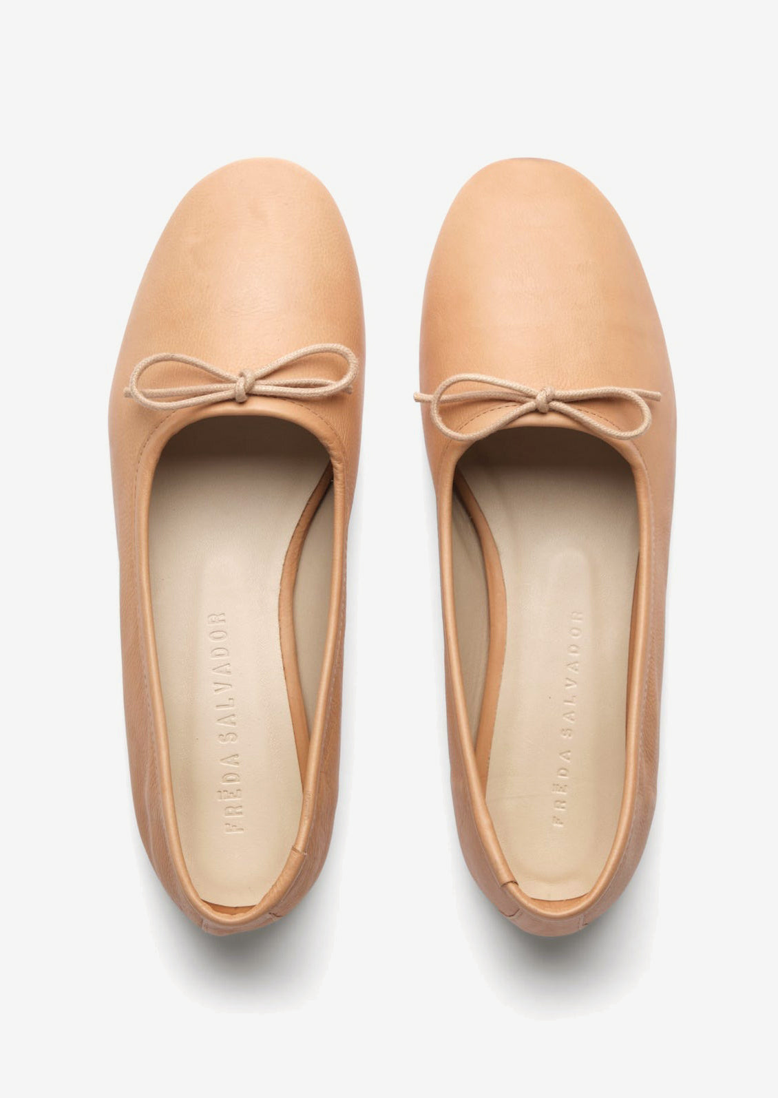 A pair of leather ballet flats with round toe in neutral tan leather.