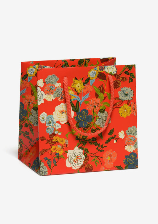 A small square shaped gift bag in red with multicolor rose garden print.