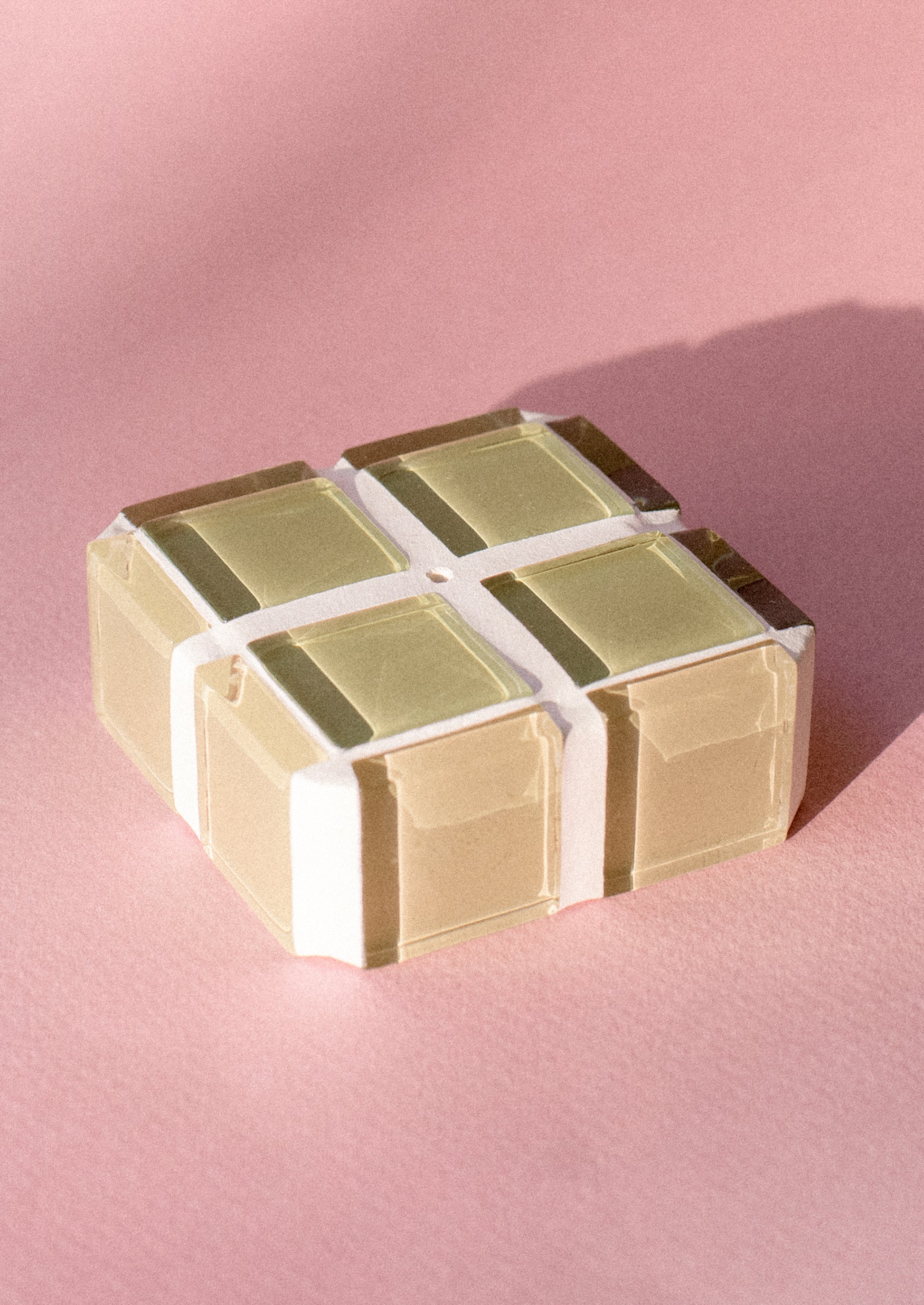 A square cube shape incense holder made up of sage green glass tiles.