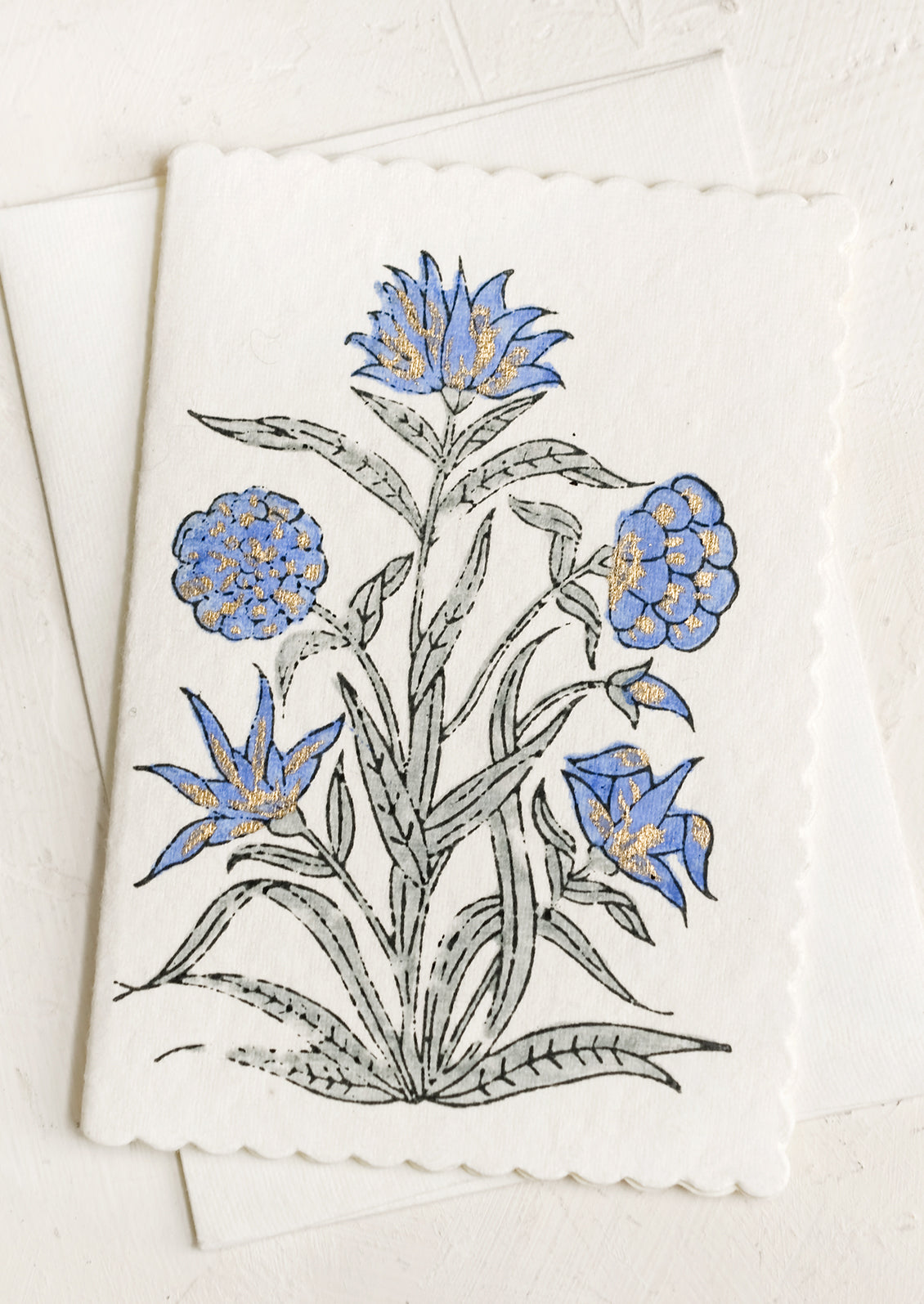 A block printed periwinkle floral card with scalloped edges.