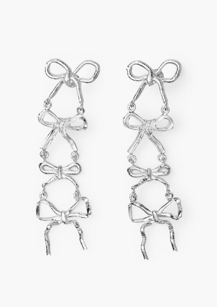 A pair of silver earrings with four bows, in slightly different shapes, stacked on top of each other.