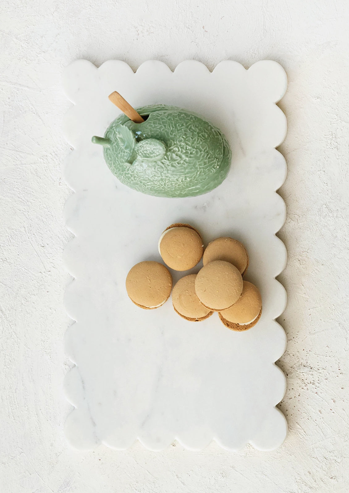 A white marble serving board with scalloped edge.