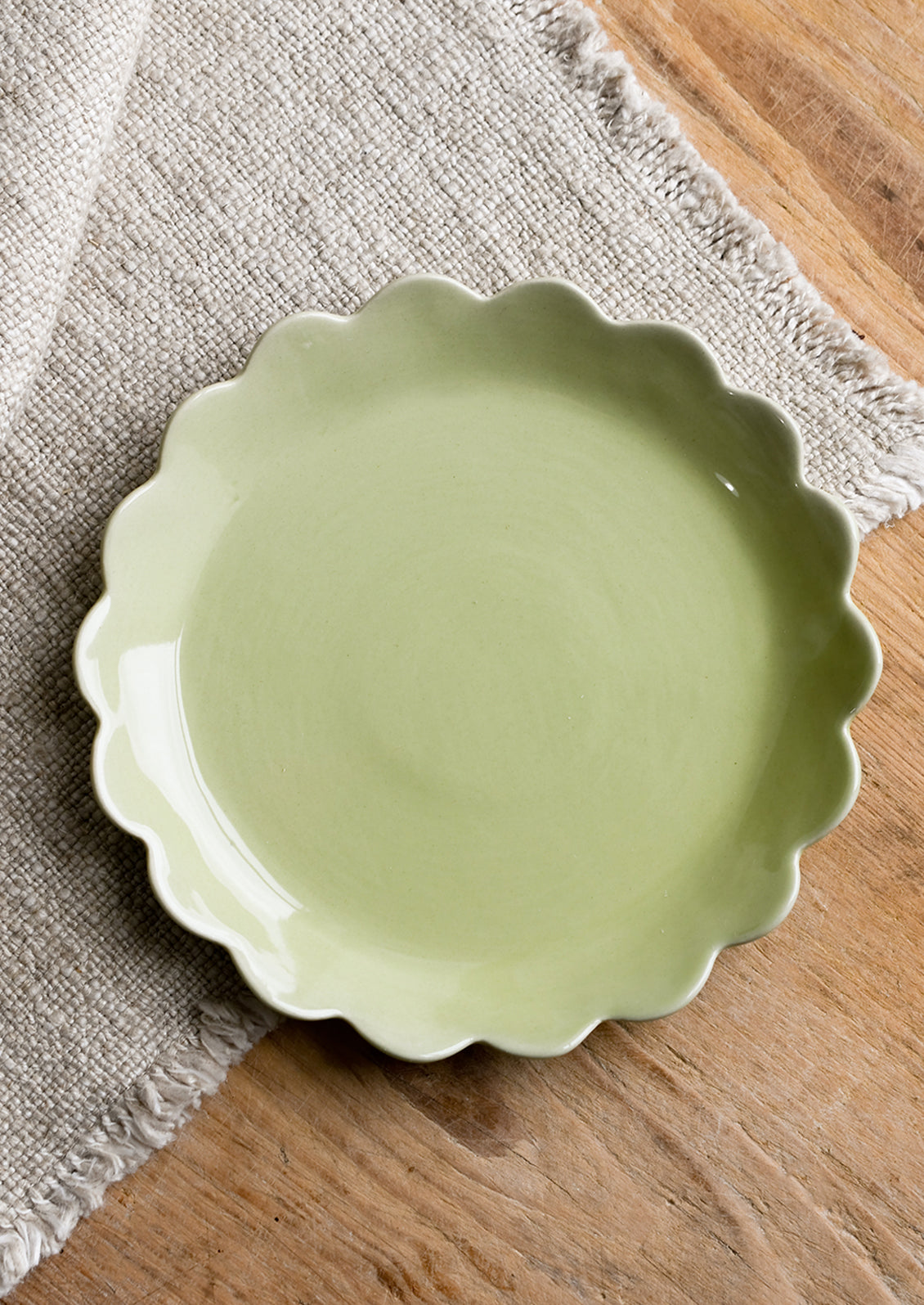 A scalloped ceramic dessert plate in green.