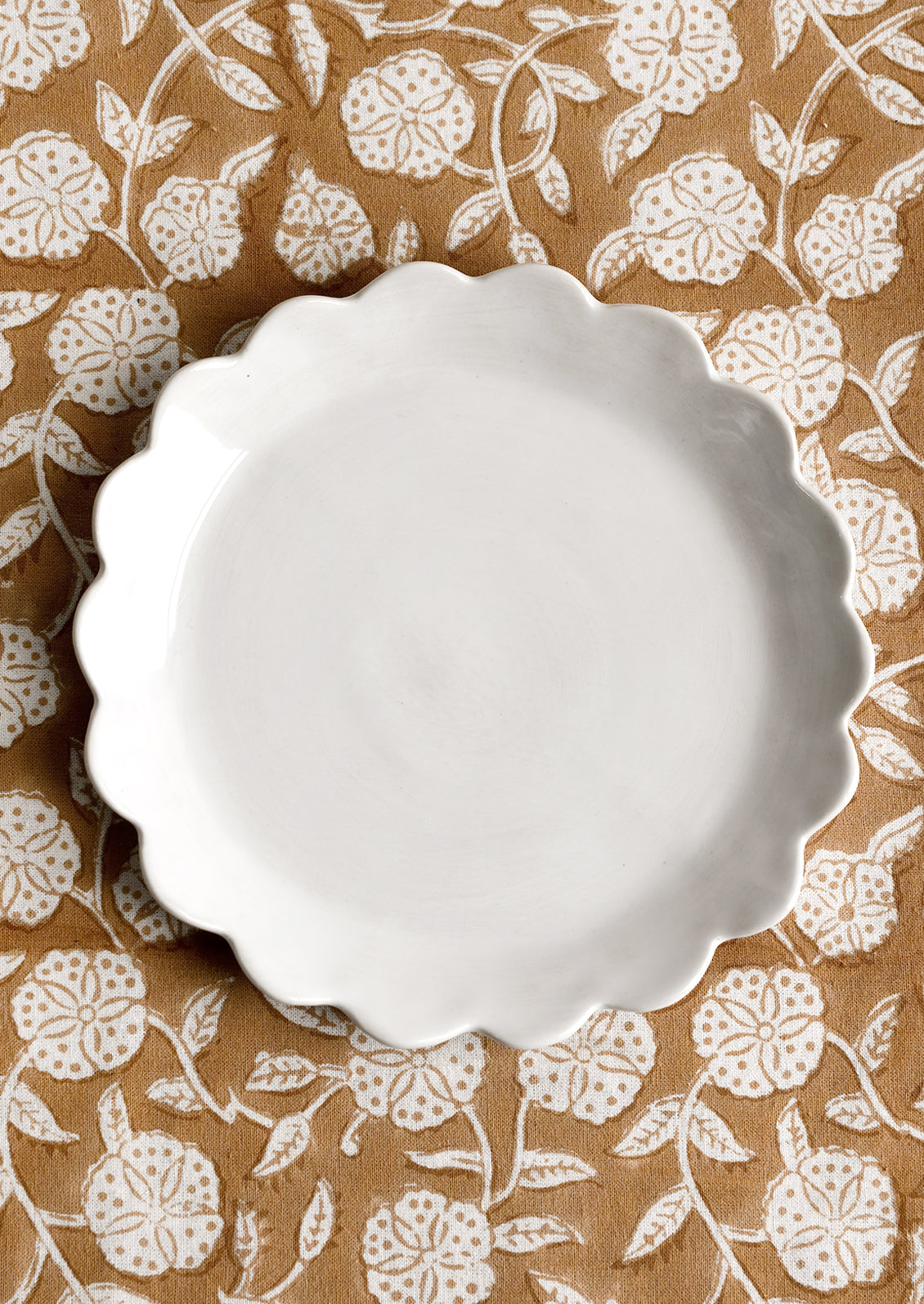 A scalloped ceramic dessert plate in white.