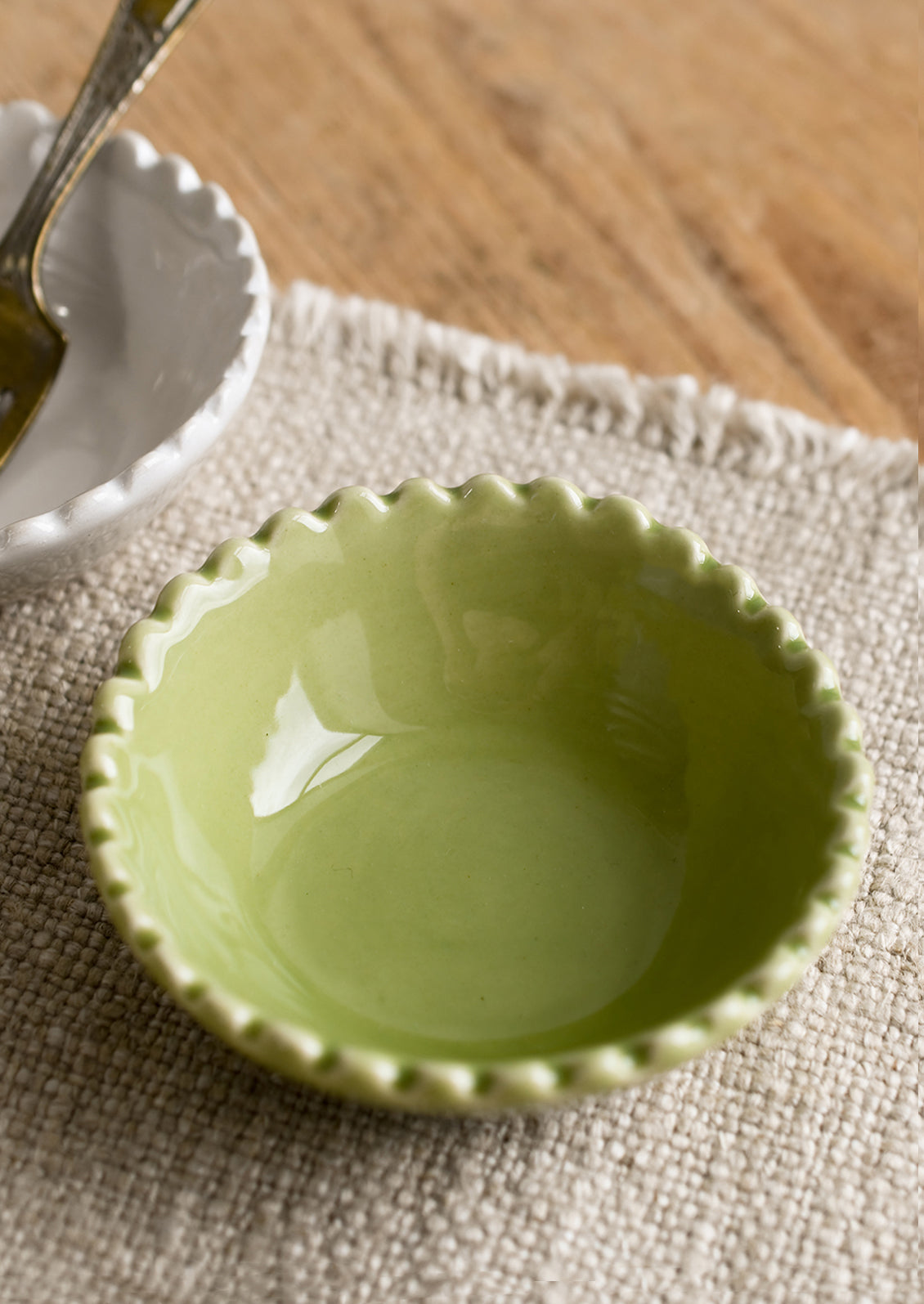 A small ceramic bowl with scalloped rim in green.