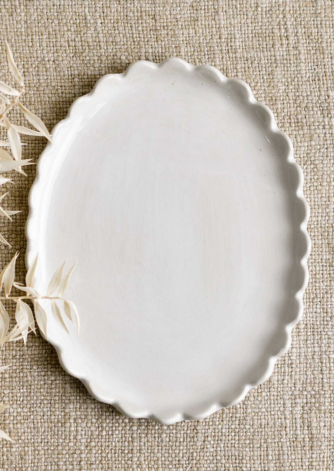 A white ceramic oval tray with scalloped edges.