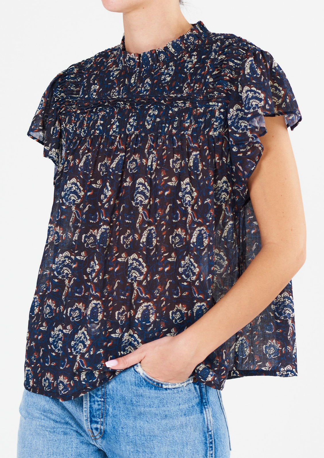 A woman wearing a blue, white and rust floral printed flutter sleeve top.