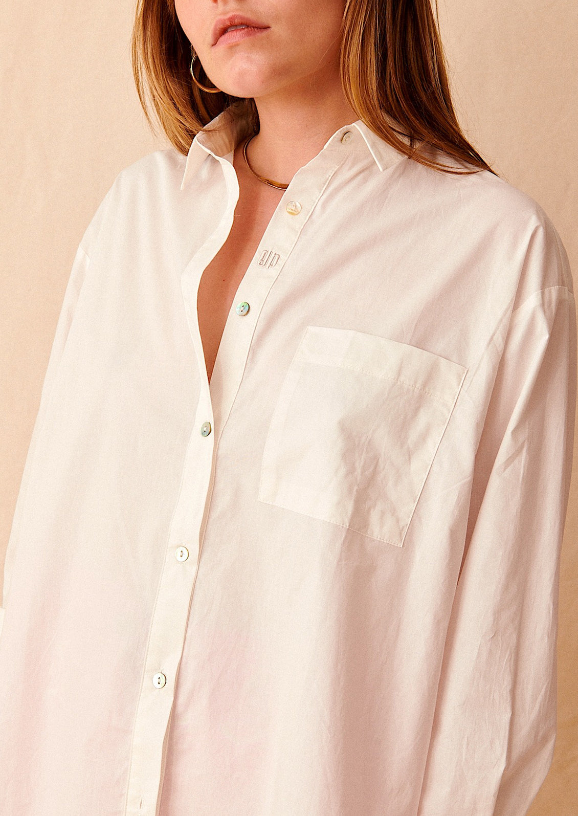 A woman wearing an oversized white cotton shirt.