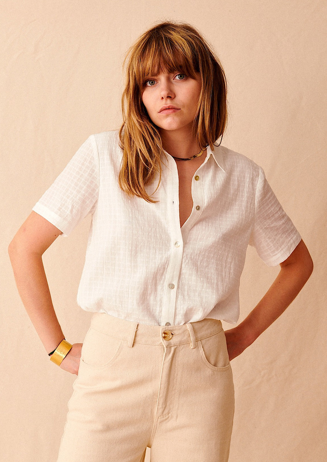 A woman wearing a short sleeve collared shirt with tonal grid texture.