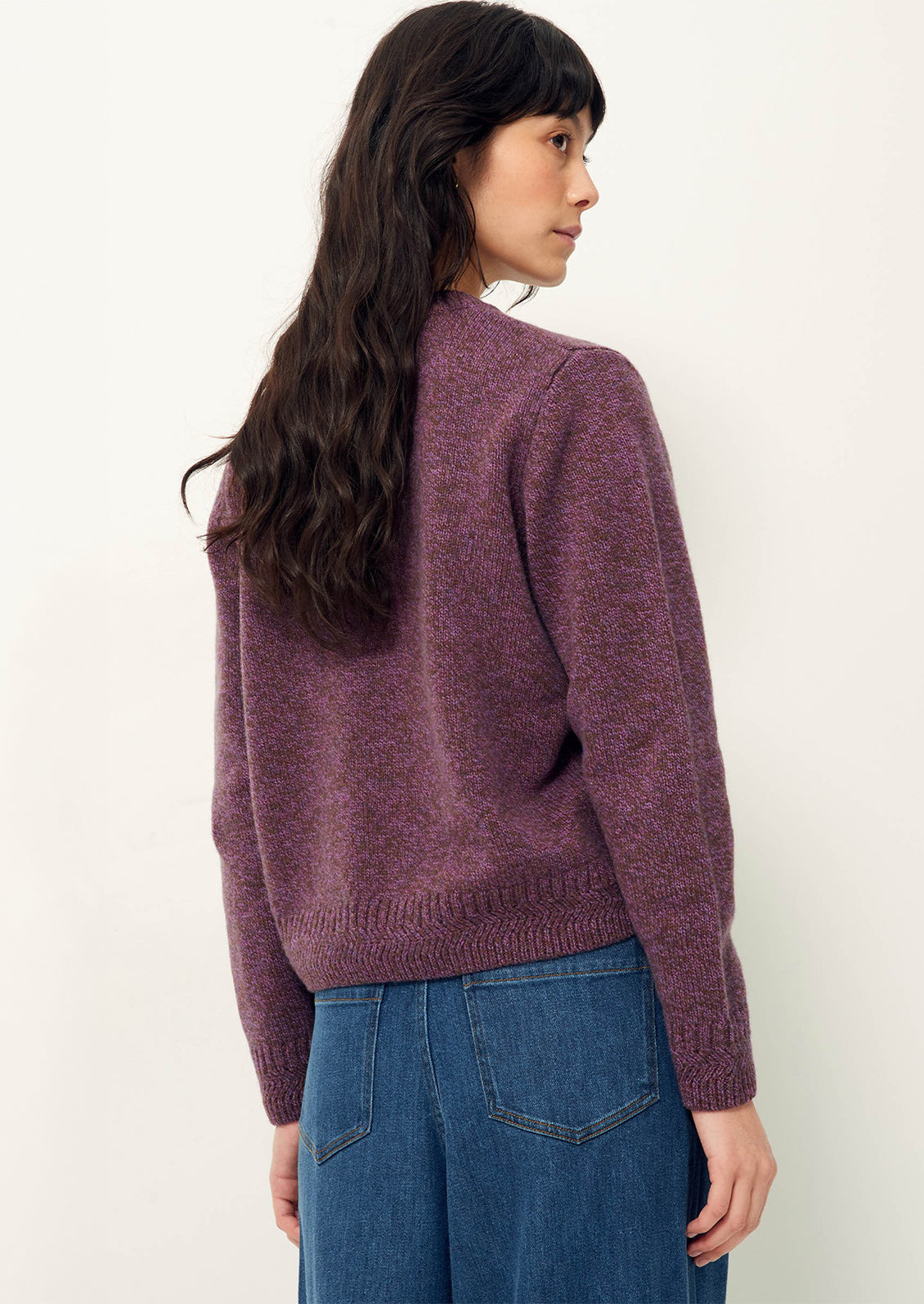 A woman wearing a crew neck sweater in marled purple yarn..