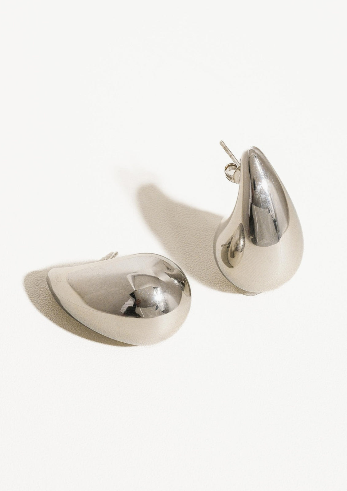 A pair of chunky, teardrop-shaped earrings in silver.