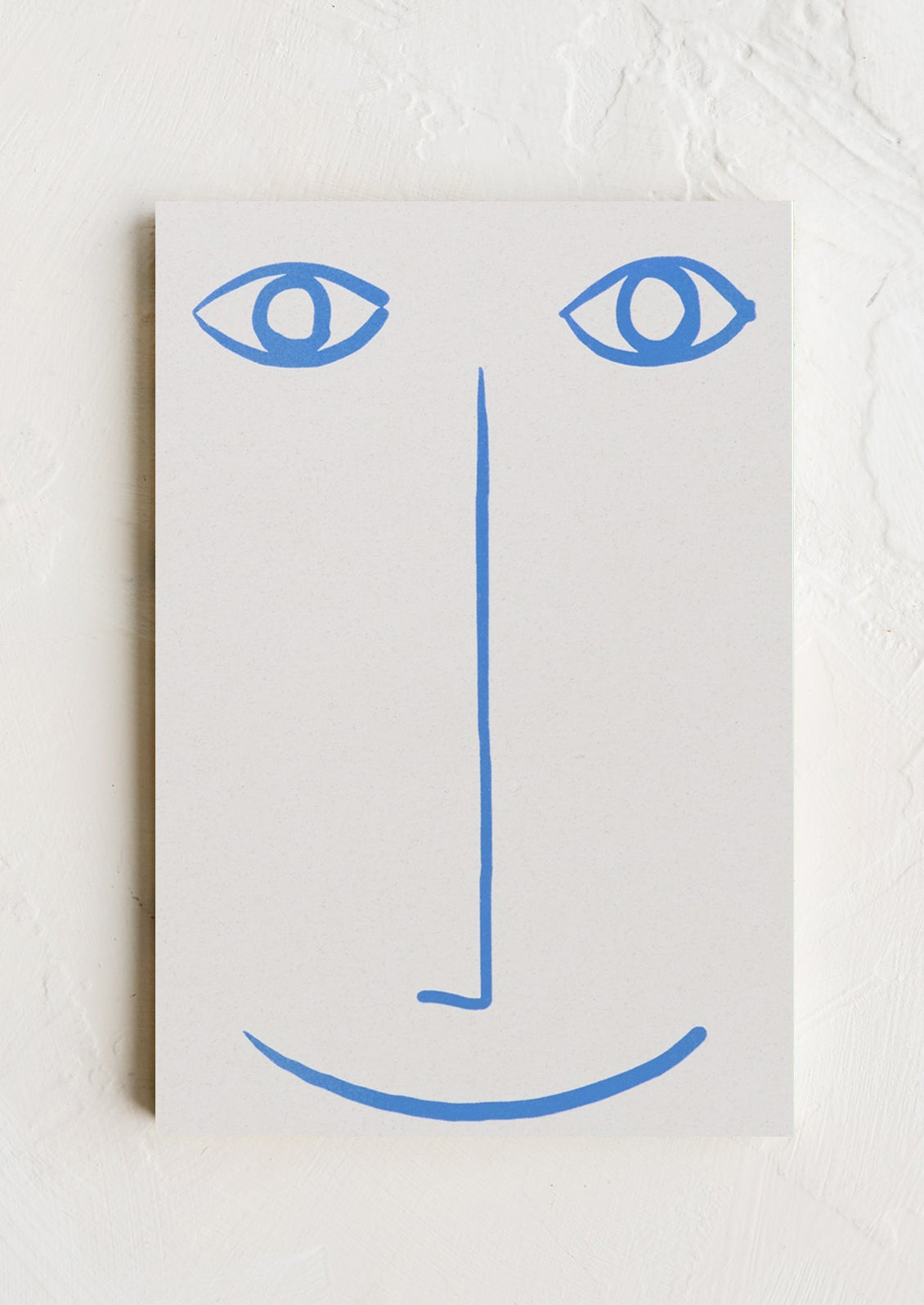 A white notepad with blue printed smiley face.