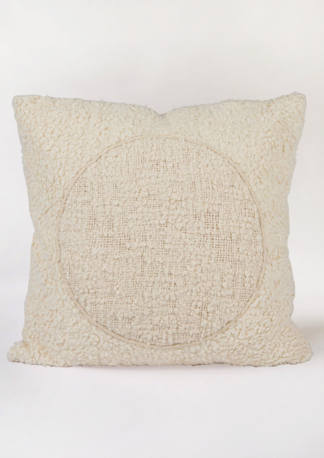 A cream colored throw pillow in soft sherpa material with tonal circle design at center.