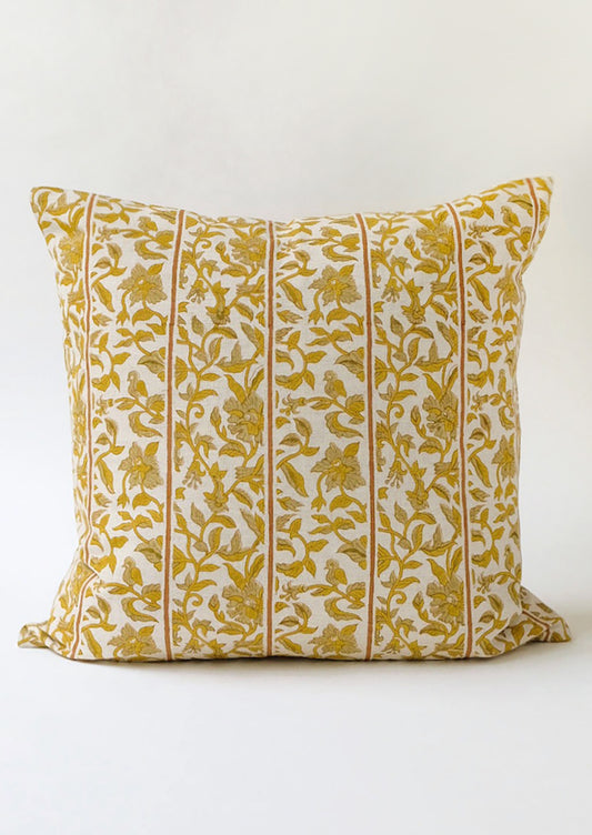 A block printed pillow with vertical stripes amidst yellow floral pattern.
