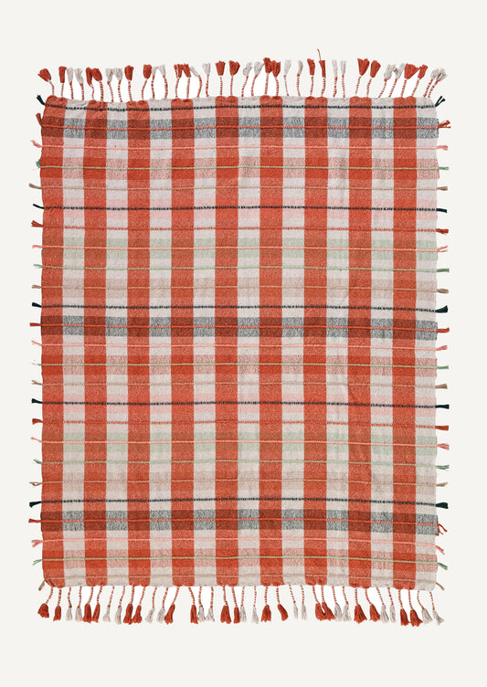 A cotton blend throw blanket in orange and cream plaid with multicolor tasseled stripe detailing.