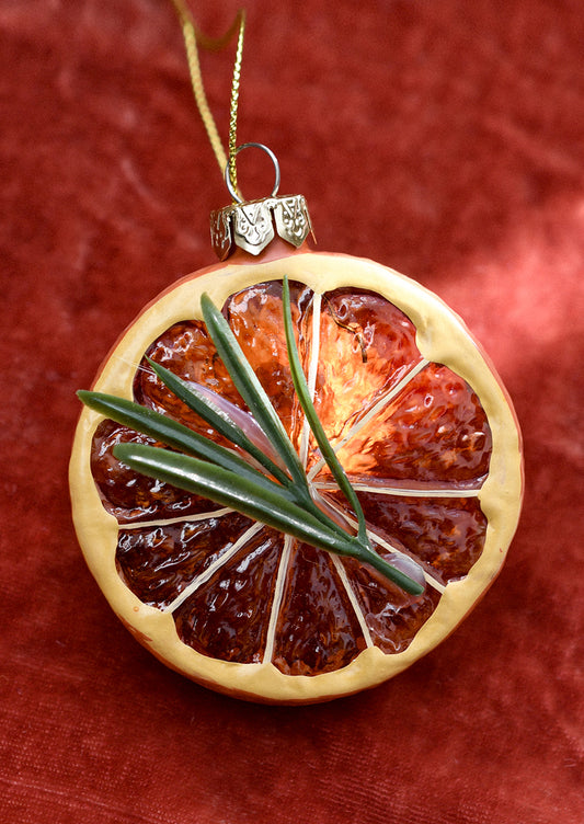 A glass ornament of an orange slice with sprig of rosemary.