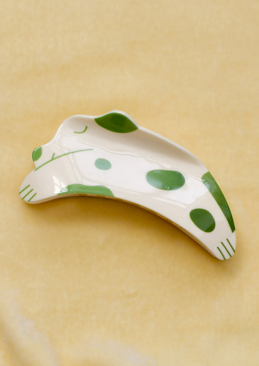 A hair claw in shape of dog, eyes closed with green spots.