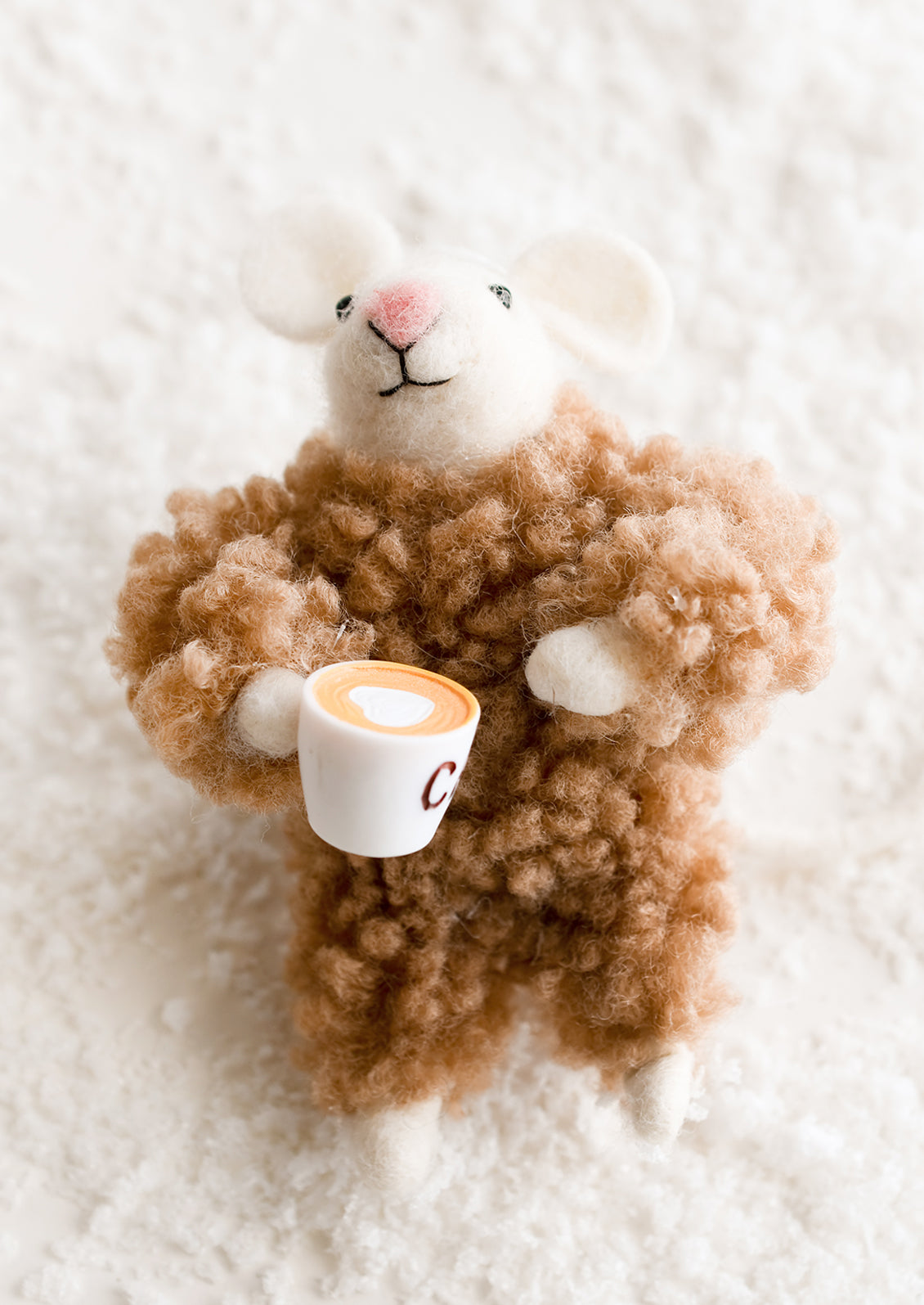 A felted mouse ornament in brown fuzzy pajamas, holding cup of coffee.