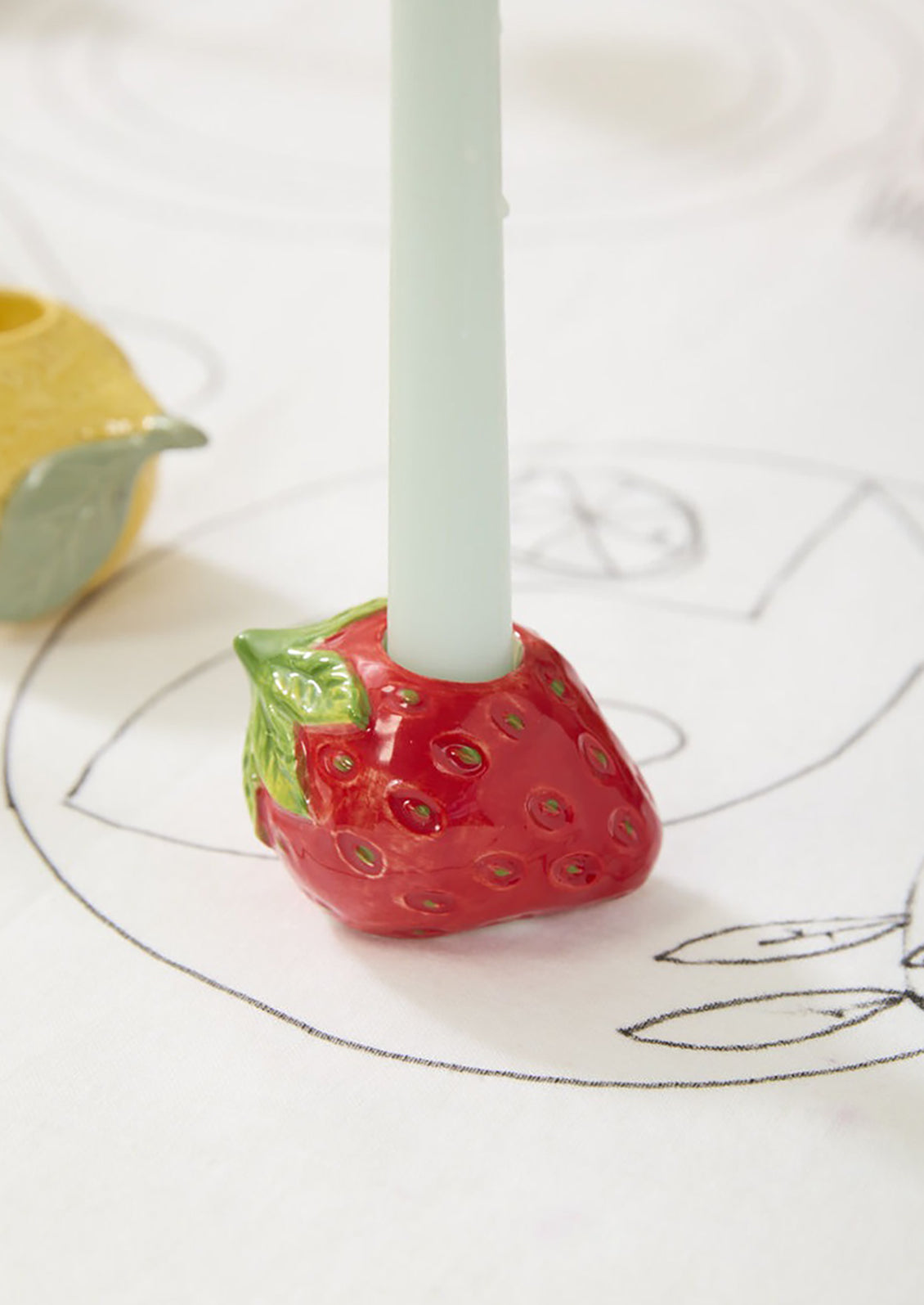 A ceramic candleholder in the shape of a red strawberry.