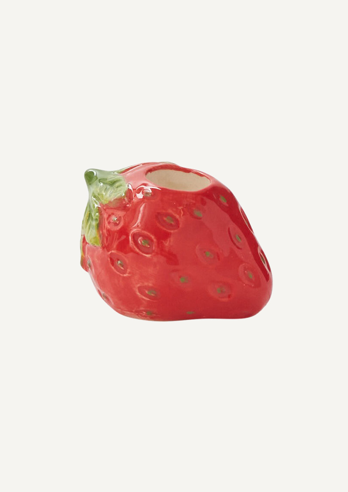 A ceramic candleholder in the shape of a red strawberry.