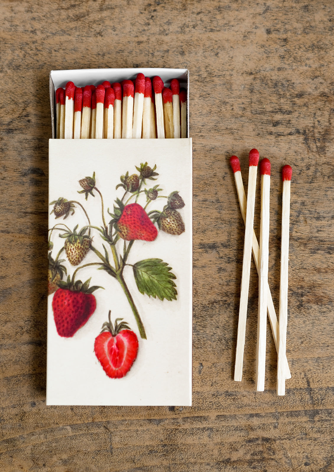 A box of long red tipped matches, box has vintage-inspired strawberry illustration.