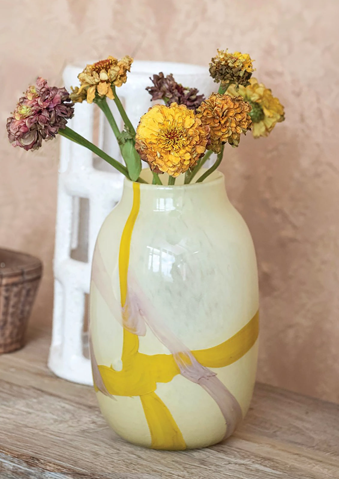 A pale yellow glass vase with bright yellow and lavender paint streaks.