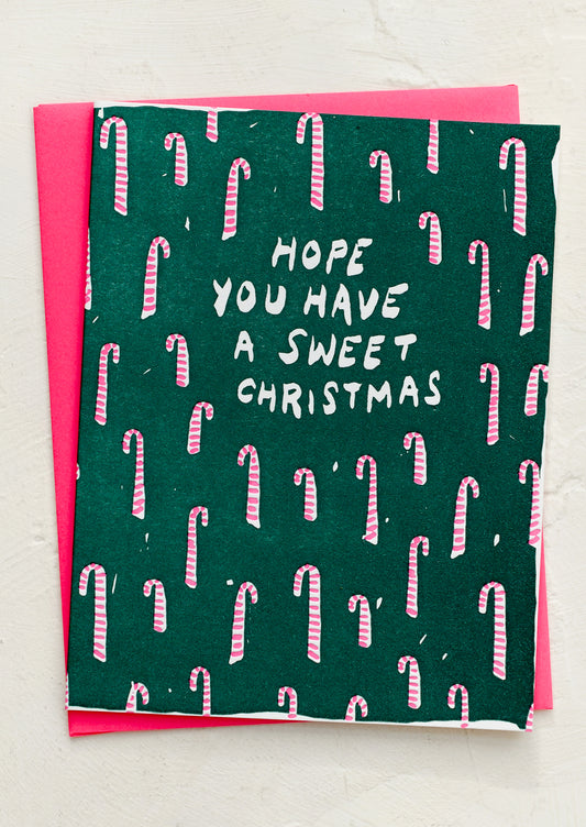 A candy cane printed card with neon pink envelope, text reads "Hope you have a sweet Christmas".