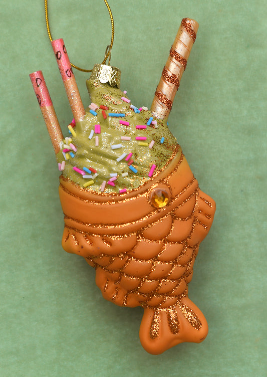 A glass ornament of taiyaki holding green soft serve.