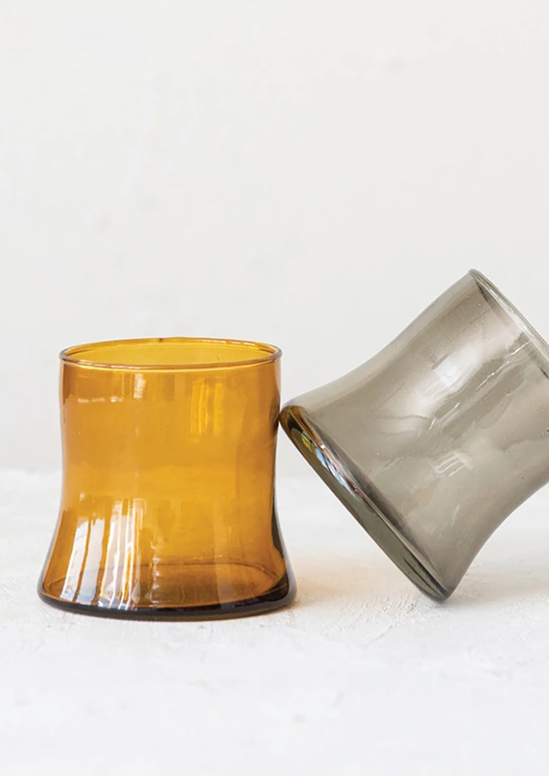 Two tapered drinking glasses in amber and smoke.