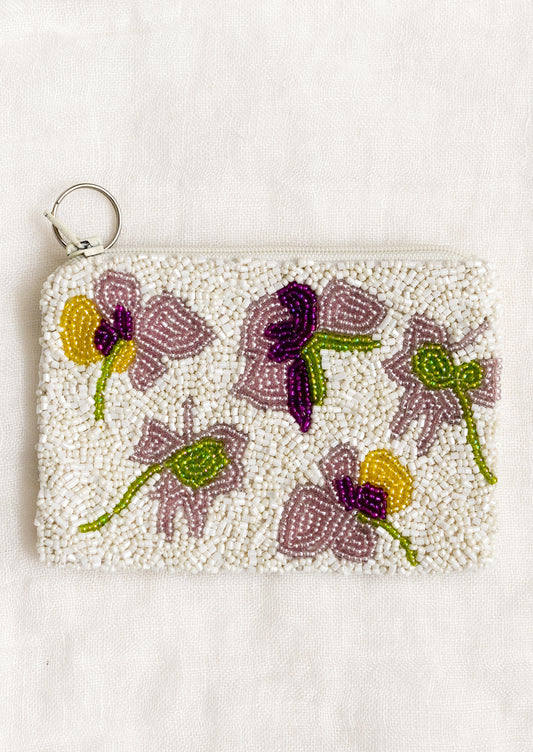 A beaded coin pouch with green, purple and yellow floral design.