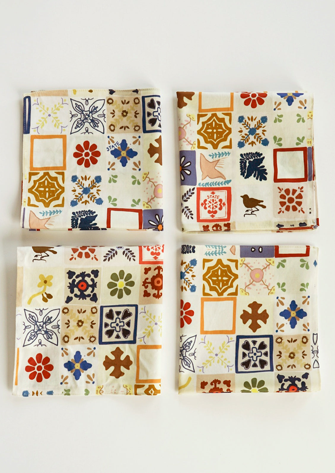 A set of four colorful, mixed tile print cloth napkins.