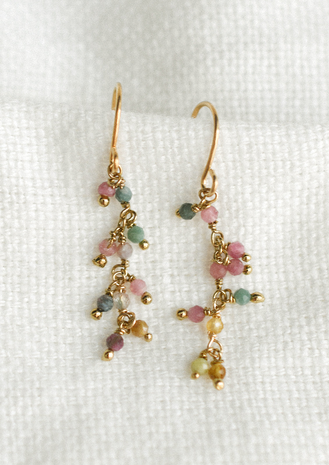 A pair of delicate dangle earrings with colorful tourmaline beads.