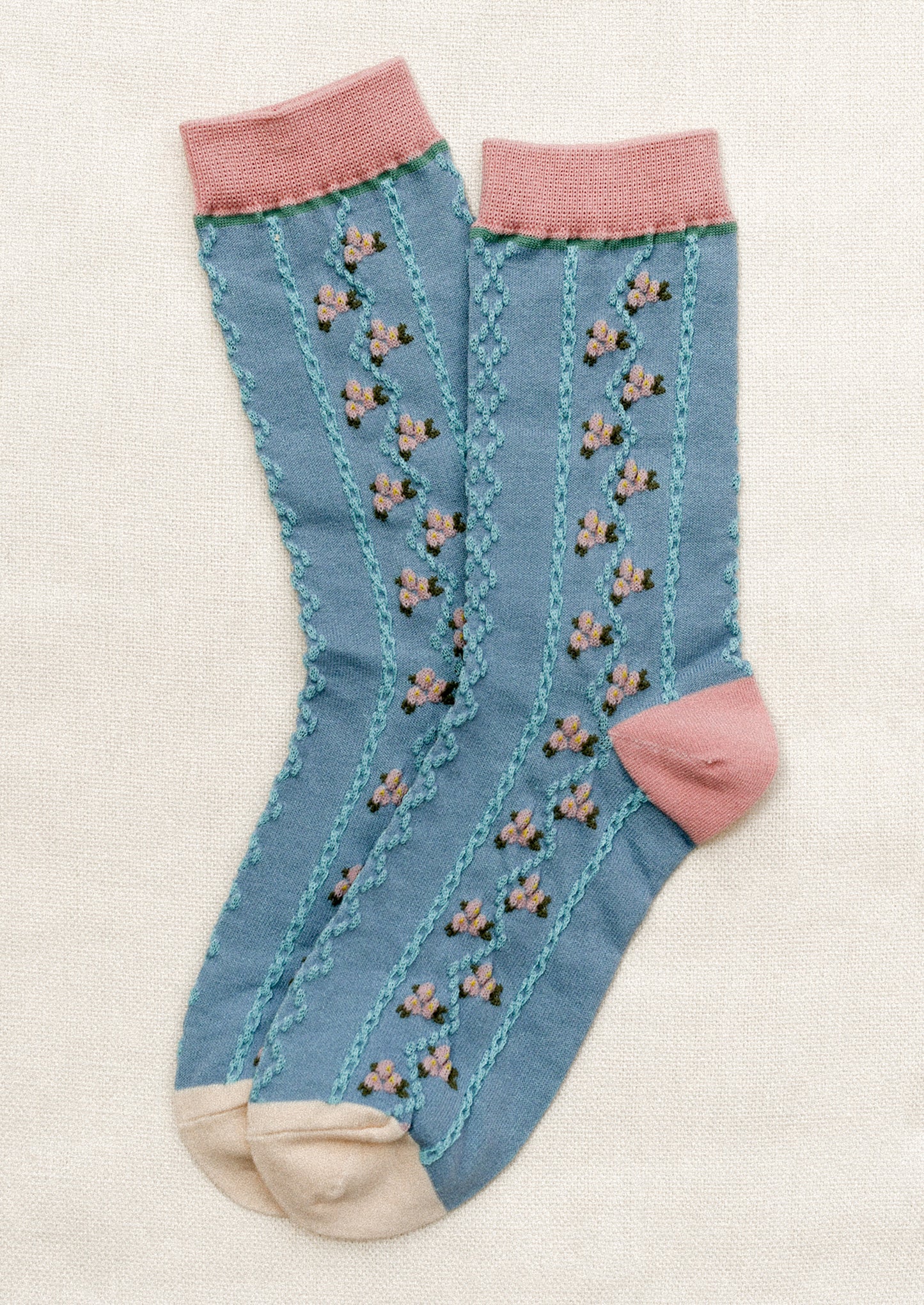 A pair of blue socks with pink vertical floral pattern and pink trim.