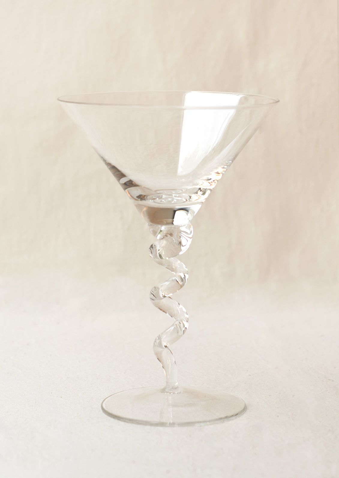 A clear martini glass with twisted stem shape.