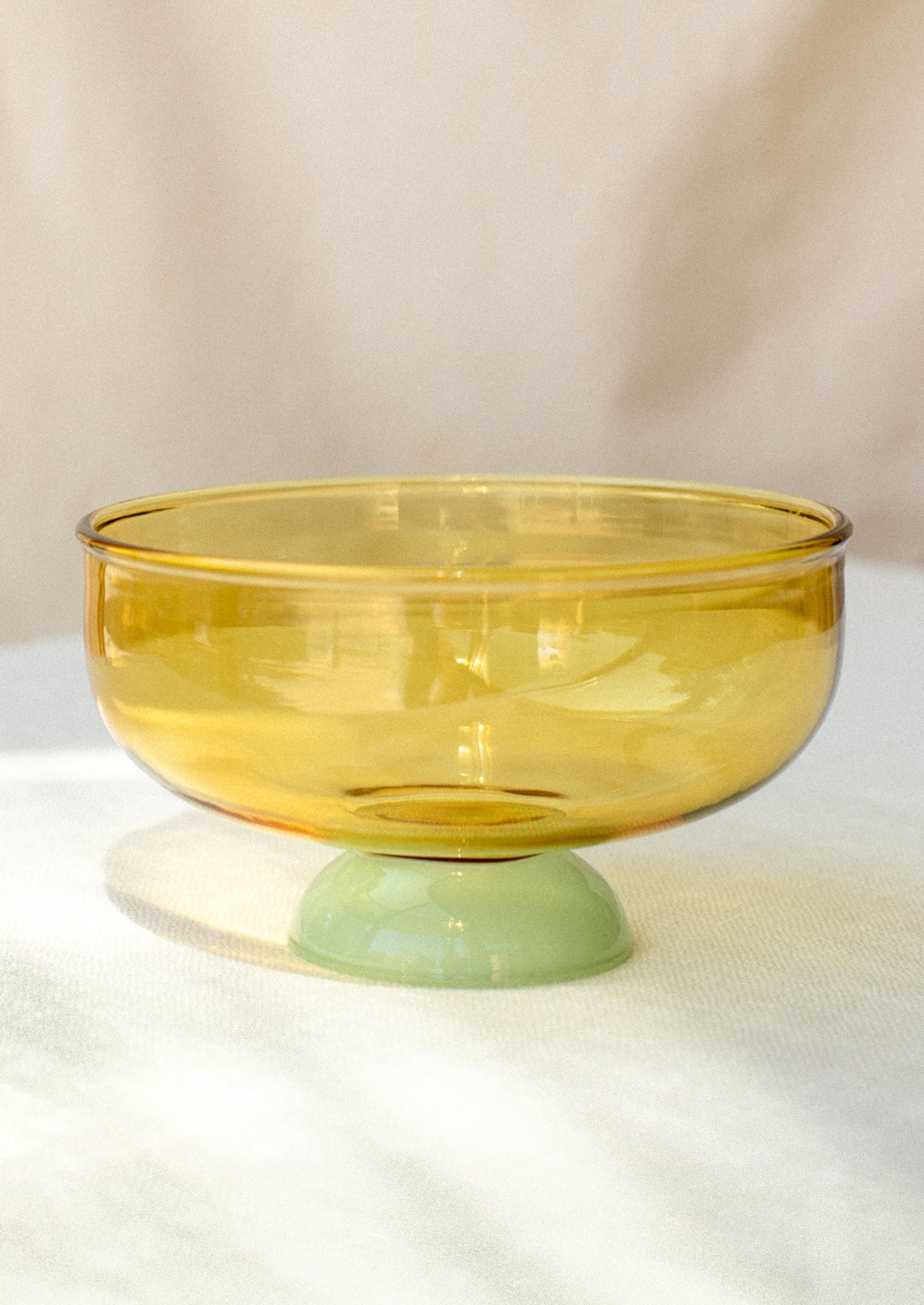 A shallow glass bowl with transparent amber top and opaque mint foot.