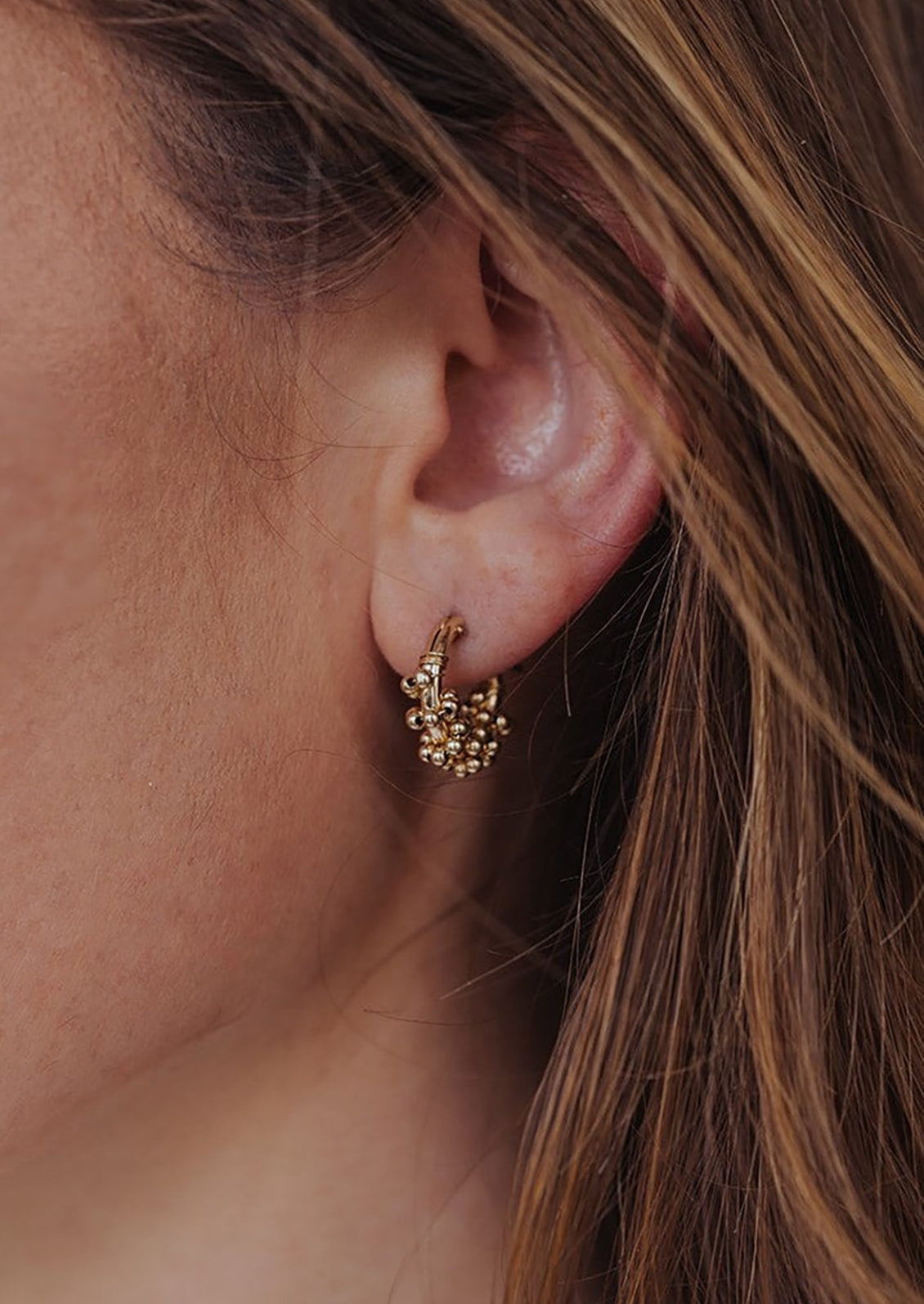 A pair of gold hoop earrings with gold beads.