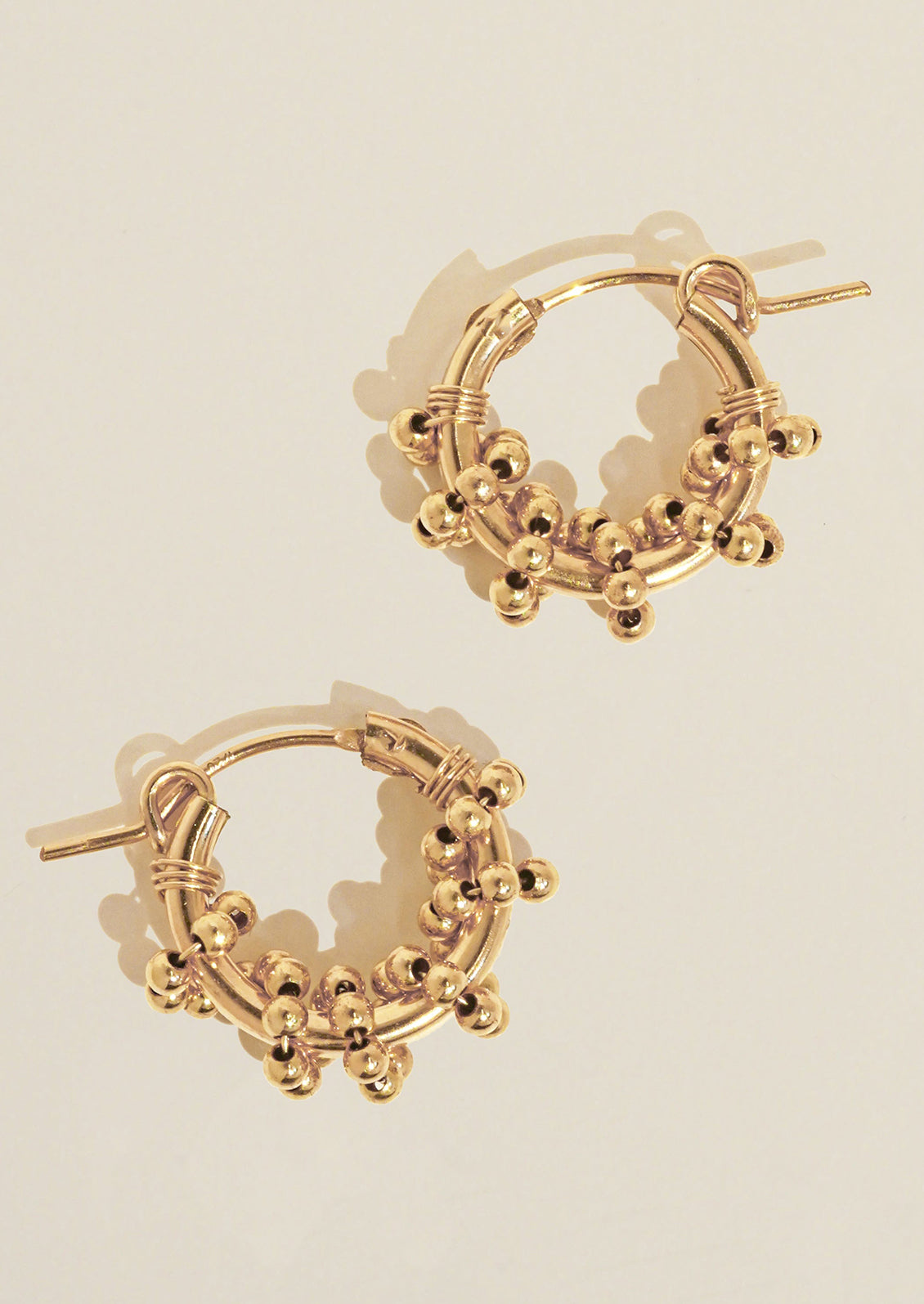 A pair of gold hoop earrings with gold beads.